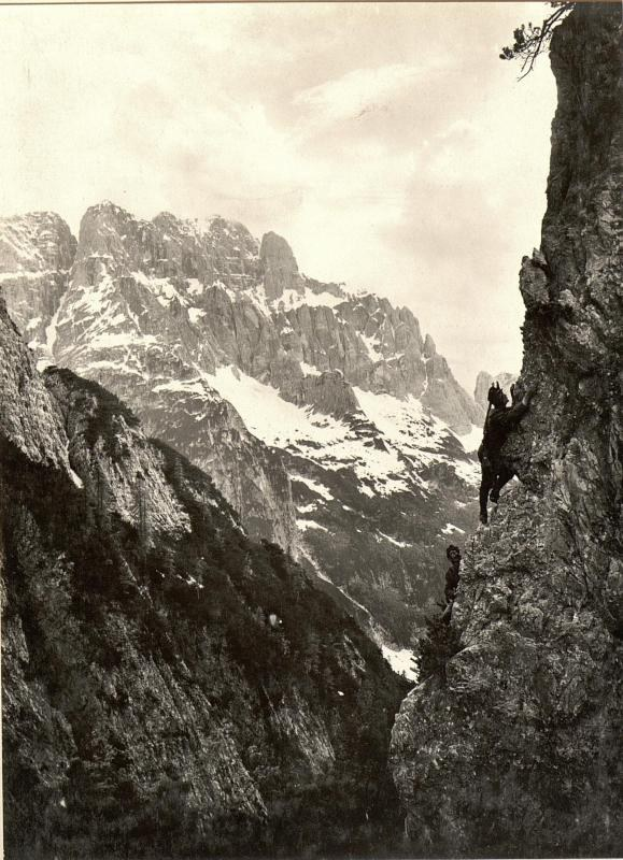 Schwarz-weiß-Fotografie eines Mannes, der einen schneebedeckten Berg erklimmt, mit drei markanten Gipfeln im Hintergrund, betitelt mit "Gustav Klimt - Die drei Gipfel".