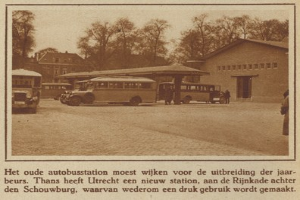 Altes Schwarz-Weiß-Foto eines Bushäuschens mit mehreren geparkten Bussen, Menschen in der Nähe, Bäumen und Gebäuden im Hintergrund und Text unten.