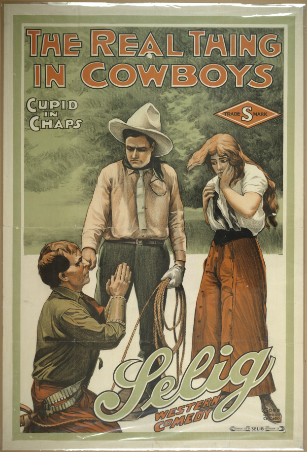 Plakat an einer Wand mit drei Personen, zwei Männern mit Cowboyhüten und einer Frau in einem langen Kleid, mit der Aufschrift "The Real Thing in Cowboys" darüber auf einem hellgelben Hintergrund.