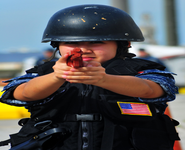 Eine weibliche Polizeibeamtin in Uniform mit einer Waffe in der Hand, mit einem unscharfen Hintergrund.