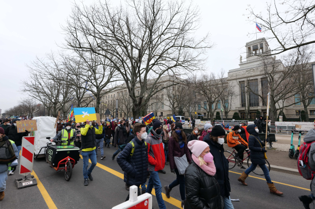 Eine große Gruppe von Menschen marschiert auf einer Stadtstraße mit Schildern und Transparenten, einige fahren Fahrräder, vor einem Gebäude unter einem klaren blauen Himmel in Washington, D.C. am 21. Januar 2020.