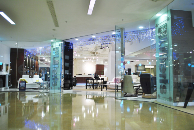 Innenansicht eines möbelgefüllten Ladens mit Stühlen, Sofas, Tischen und anderen Gegenständen, mit sichtbarem Boden und Deckenlicht sowie einem Friseursalon-Schild im Hintergrund.