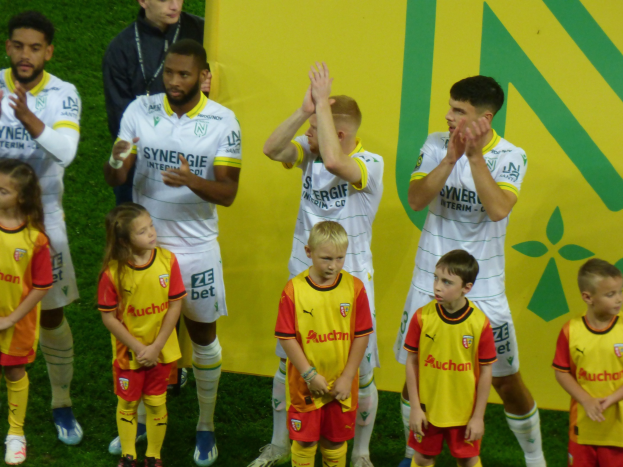 Eine Gruppe von Fußballspielern in Uniformen klatscht auf einem Ligue 1-Feld in celebration