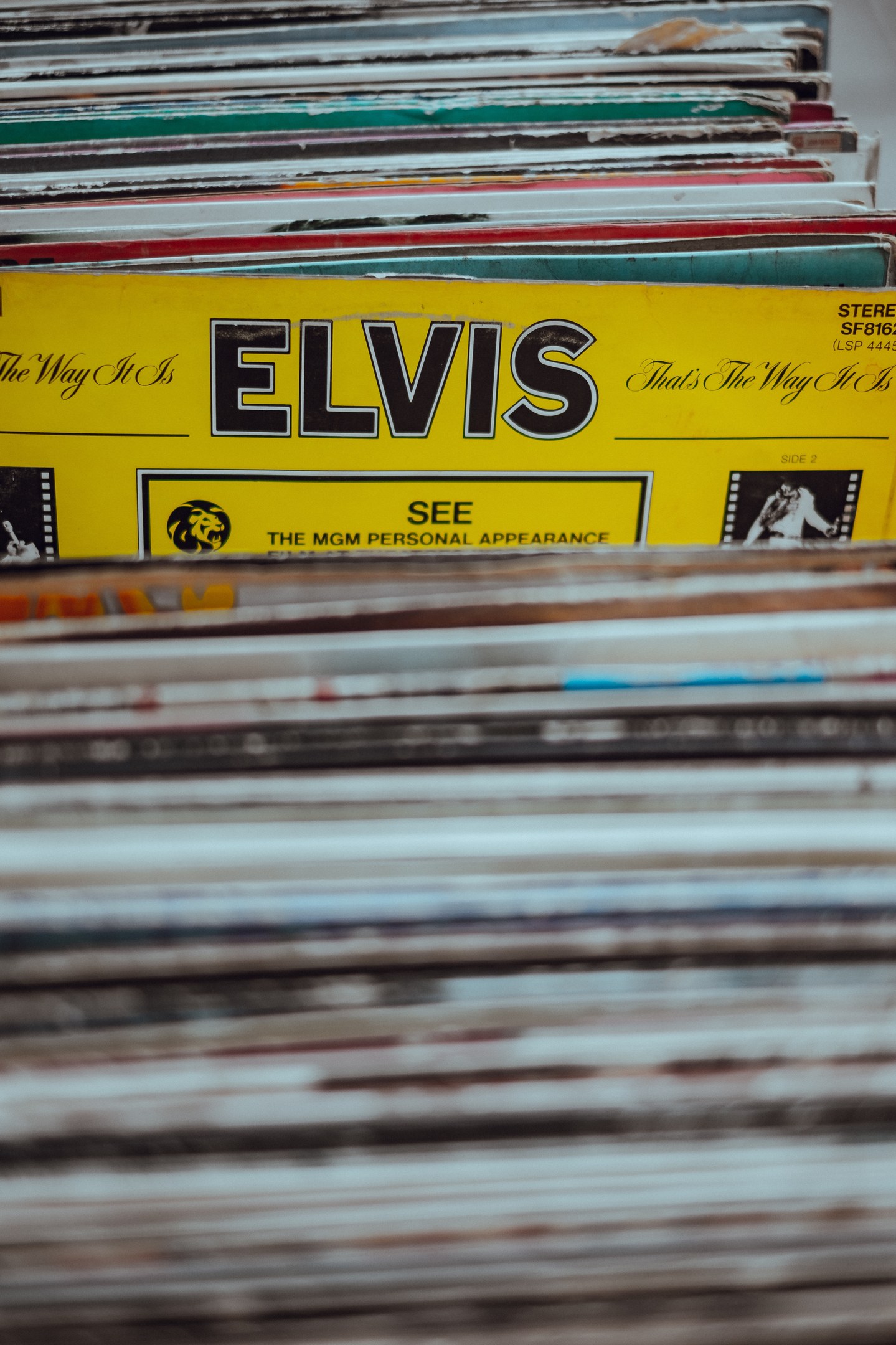 Ein ordentlicher Stapel von Elvis Presley-Platten mit sichtbaren Titeln auf einem leicht unscharfen Hintergrund.