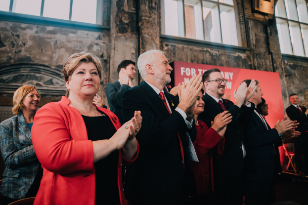 Eine Gruppe von Menschen, die vor einer Menge jubeln, mit einem Banner im Hintergrund, das "Wir haben die Wahl gewonnen." zeigt