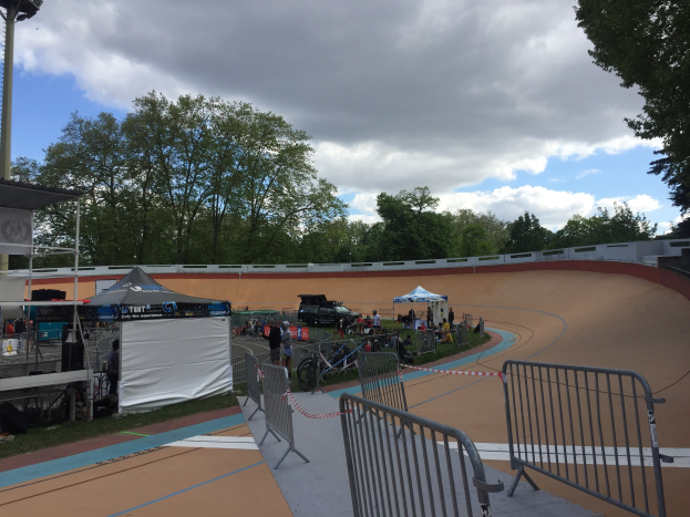 Gruppe von Fahrradfahrern, die BMX-Räder auf einer Schmutzstrecke bei den UCI-BMX-Weltmeisterschaften 2018 fahren, mit Zuschauern, Zelten und Fahrzeugen im Hintergrund.