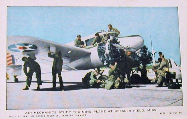 Gruppe von Menschen, die um ein Trainingsflugzeug auf einer Landebahn mit einem klaren blauen Himmel im Hintergrund stehen, beschriftet mit "Air Mechanics Study Training Plane at Keesler Field, Miss."