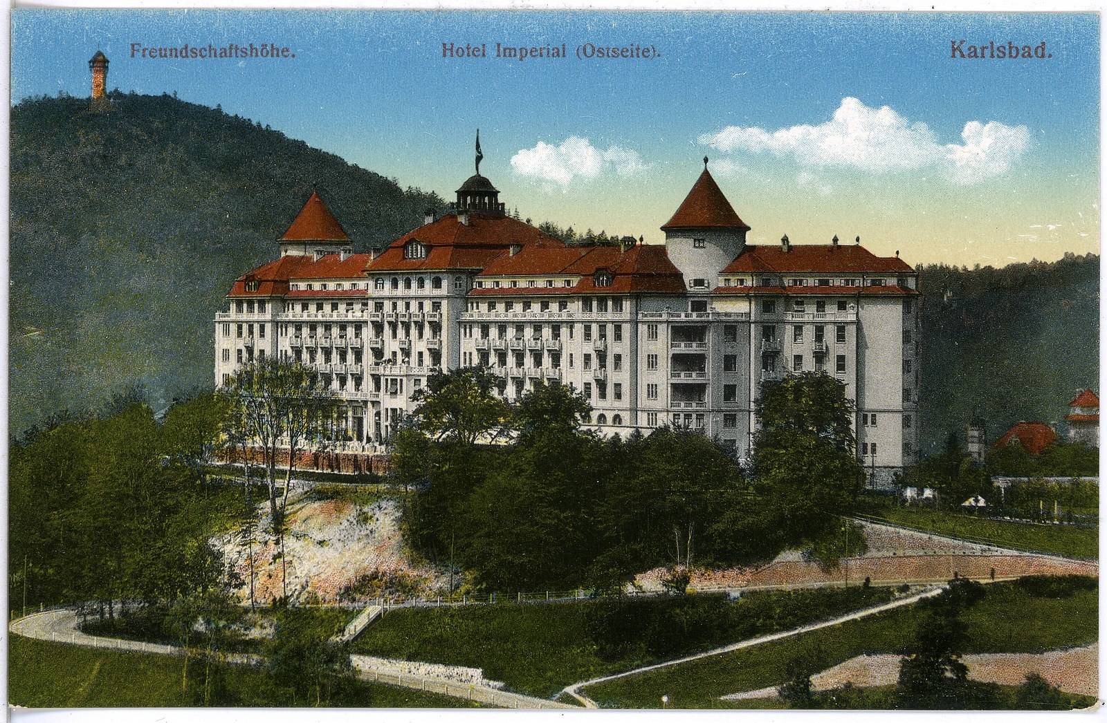 Alte Postkarte des Hotel Imperial in Karlsbad, Deutschland, zeigt ein großes Gebäude mit Fenstern, umgeben von Bäumen, Pflanzen, Gras, einem Pfad, einer Baumgruppe, Hügeln und einem bewölkten Himmel, mit Text oben.