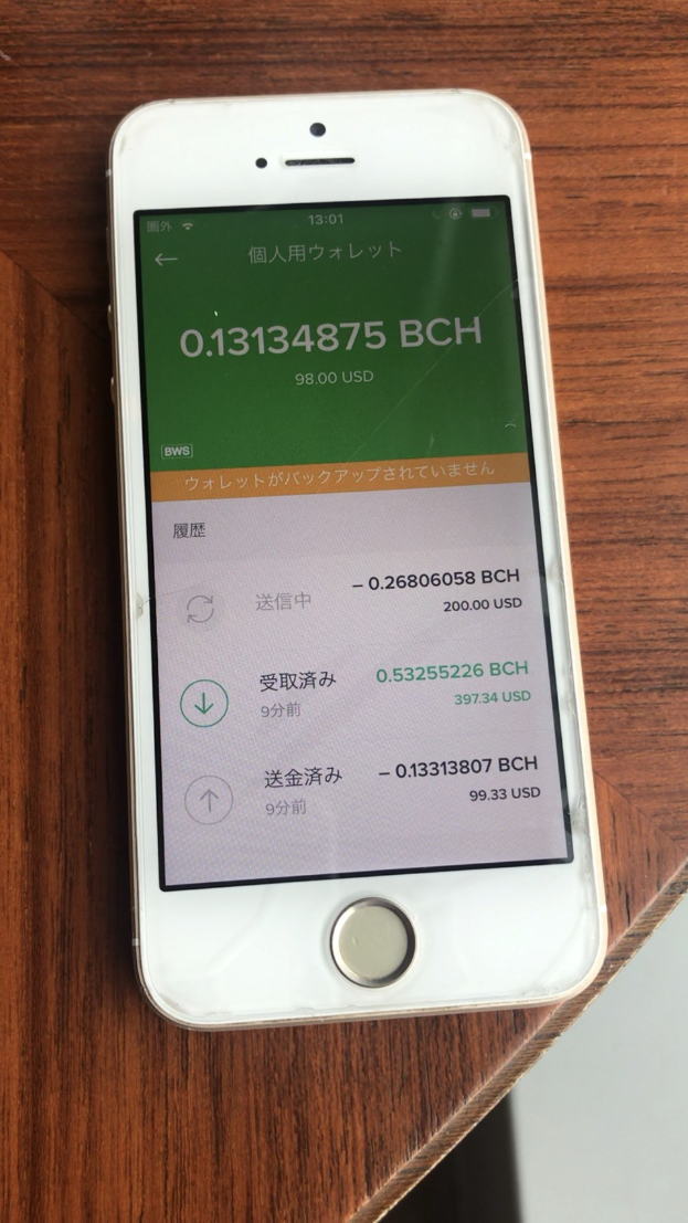 Ein weißes iPhone auf einem Holztisch zeigt Text, der "Wie man online Geld verdienen kann" und begleitende Zahlen anzeigt.