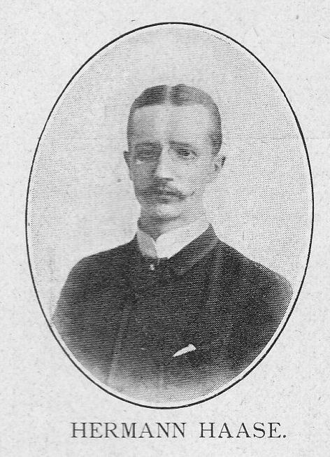 Schwarz-weißes Porträt des deutschen Komponisten und Pianisten Hermann Haase in einem Anzug mit Schnurrbart, ernster Miene und deutschem Text unten.