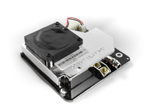 Nahaufnahme eines schwarzen und silbernen Kühlkörpers mit mehreren daran befestigten Drähten auf einer weißen Oberfläche.