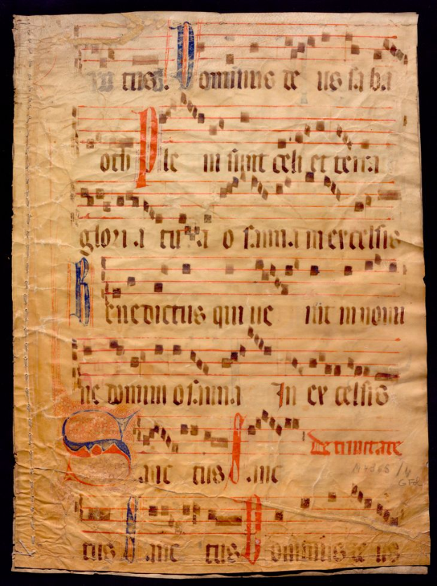 Ein illuminiertes Manuskript mit Musiknotation auf einem Blatt Papier vor dunklem Hintergrund, gefüllt mit Text und Musiksymbolen, die ein komplexes Design ergeben.