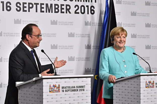 Bundeskanzlerin Angela Merkel und Frankreichs Präsident François Hollande lächeln auf einem Podium mit einem Banner "Bratislava-Gipfel 2016" dahinter.