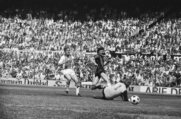 Schwarzes und weißes Bild von Männern, die auf einem Feld Fußball spielen, mit Zuschauern im Hintergrund und einem Banner mit der Aufschrift "Bundesliga 1978-79 Ajax 1-1 Hannover 96".