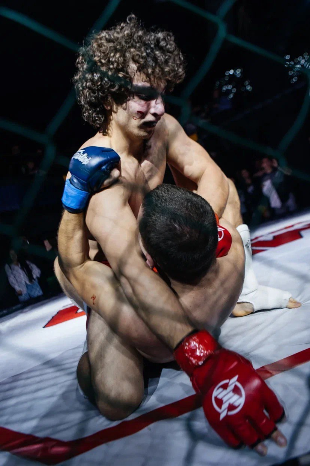 Zwei Männer in einem MMA-Ring in einem Kampf, wobei einer einen mächtigen Tritt landet.