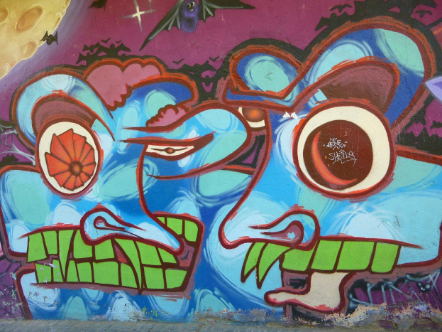 Ein lebendiges, farbenfrohes Wandgemälde mit Graffiti-Kunst an der Seite eines Gebäudes, das verschiedene Formen und Farbtöne zeigt.