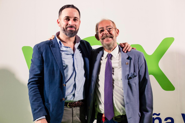 Zwei Männer in Anzügen lächeln nebeneinander vor einer Wand, wobei der Mann rechts eine Brille trägt; ein Schild im Hintergrund trägt die Aufschrift "Vodafone und Vodacom kündigen Partnerschaft an."