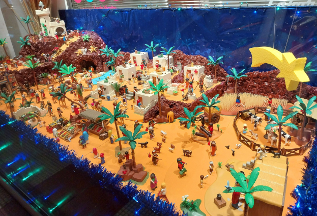 Vitrine voller verschiedener Lego-Steine und -Teile auf einem Tisch, umgeben von Spielzeugen und dekorativen Elementen, mit beleuchteter Wand im Hintergrund.