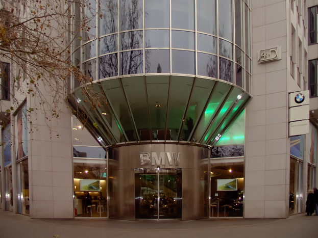 Moderner Glasturm-BMW-Hauptsitz in Frankfurt, Deutschland, mit Menschen davor und einem Baum links.