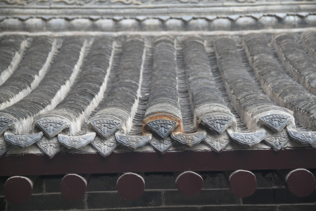 Nahaufnahme eines gekachelten Dachs mit detaillierten Entwürfen an einem Gebäude.