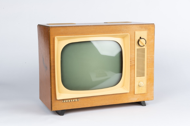 Ein altmodischer Fernseher mit Holzrahmen und schwarzem Bildschirm steht auf einer weißen Oberfläche vor einem hellen weißen Hintergrund.