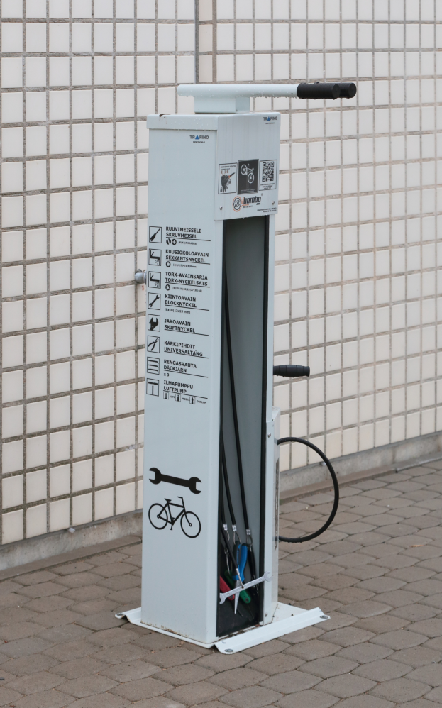 Eine Elektroauto-Ladestation an der Seite eines Gebäudes mit einer Maschine auf dem Boden und einer Wand im Hintergrund.